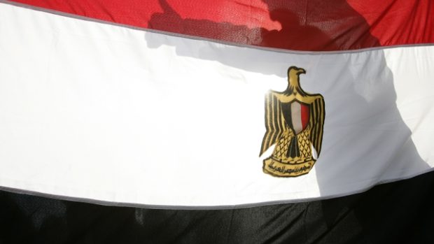 stín radujícího se demonstranata na egyptské vlajce