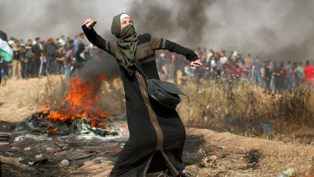 Palestinská dívka hází kámen po izraelských vojácích.