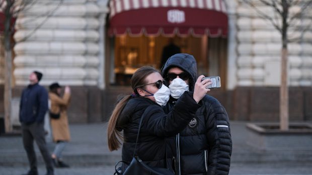Pár, který se chrání respirátory před nákazou novým koronavirem, se fotí na Rudém náměstí v Moskvě