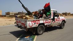 Vozidlo povstalců přejíždí portrét Muammara Kaddáfího.