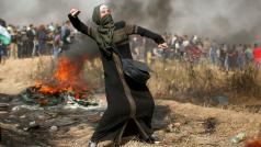 Palestinská dívka hází kámen po izraelských vojácích.
