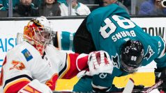 Obránce San Jose Brent Burns padá při souboji s českým brankářem Davidem Rittichem z Calgary Flames