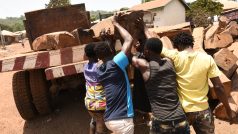 Muži nakládají čerstvě pokácené dřevo na nákladní vůz na západě Sierra Leone.