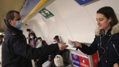 Policista rozdává v metru cestujícím roušky