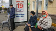 Lidé sedí na zastávce ve městě Čeboksary vedle předvolebního plakátu s nápisem „Volby 19. září 2021“