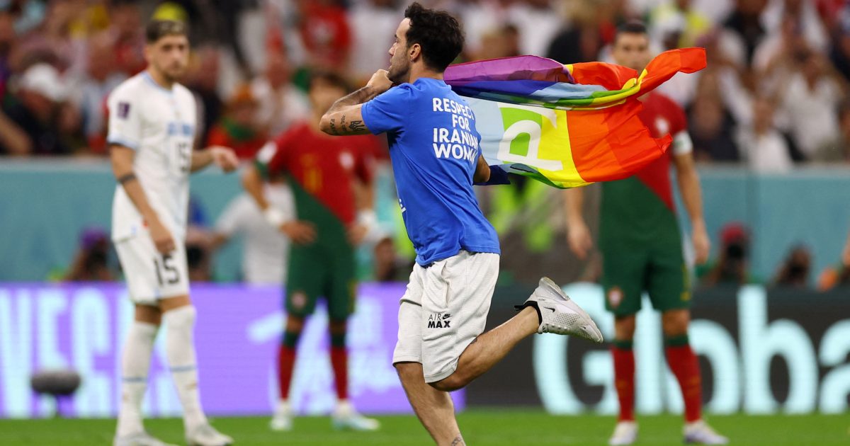 Un tifoso con una bandiera arcobaleno corre in campo durante una partita di Coppa del Mondo.  Supporta anche l’Ucraina e le donne in Iran iRADIO