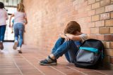 Šikanovaný chlapec pláče na školní chodbě