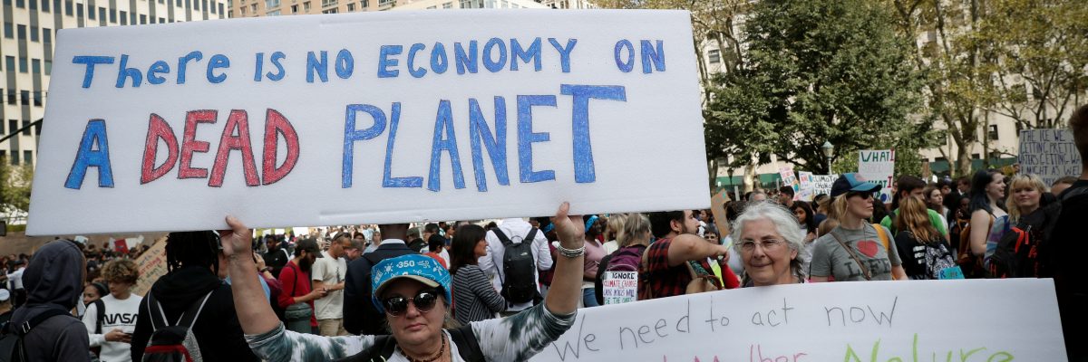 „Na mrtvé planetě žádná ekonomika není,“ hlásá transparent vlevo. „Nemáme žádnou planetu B,“ přidává druhý transparent.