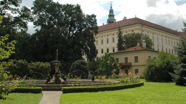 Pohled na Arcibiskupský zámek přes fontánu s vodní plochou a lekníny.