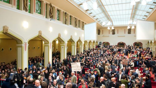 Demonstranti vnikli do budovy pražského magistrátu a společně s hlasitým pokřikem tím znemožňují zahájit zasedání.