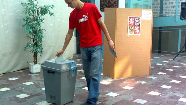 Volič vhazuje svůj lístek do urny ve volební místnosti na radnici v Krupce.