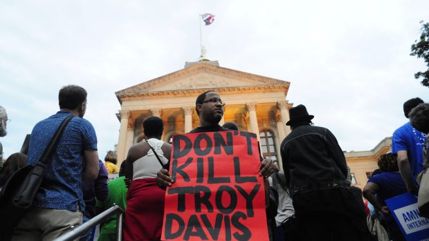 Demonstrant drží plakát s nápisem: „Nezabíjejte Troye Davise.“