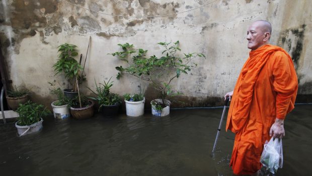 Mnich brodící se zaplavenými ulicemi historické části Bangkoku