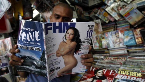 Indický prodavač tisku si prohlíží časopis s fotografií nahé herečky