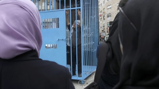 Muž ve falešném vězení, umístěném na náměstí, na dálku podporuje palestinské vězně