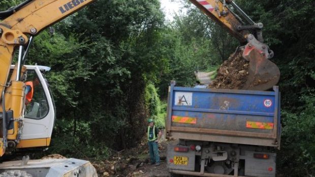 Vodohospodáři s bagrem a buldozerem odkrývají porušené potrubí, vytékající voda změnila polní cestu směřující do Divoké Šárky v koryto potoka