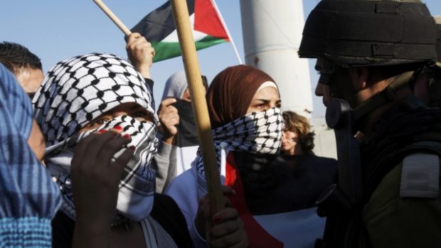 Palestinky protestují proti Izraeli tváří v tvář izraelským vojákům na checkpointu Hawara v pásmu Gazy