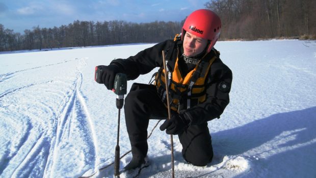 Policista Martin Racek měří tloušťku ledu na Zámeckém rybníku v Chlumci na Ústecku