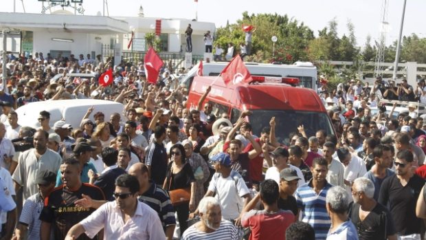 Lidé jdou podél ambulance, která veze tělo opozičního politika Muhamada Brahmího