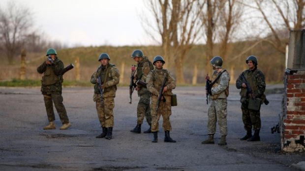Ukrajina, Kramatorsk. Ukrajinský voják (vlevo) míří na proruské aktivisty srocené před ukrajinskou leteckou základnou
