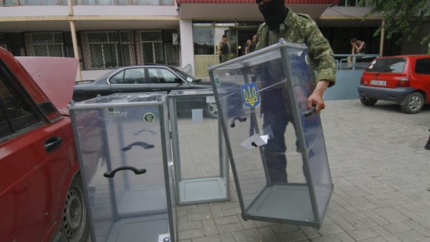 Proruský aktivista odnáší urny z volební místnosti v Doněcku, aby je mohl zničit