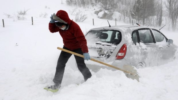 Žena vyhrabává své sněhem zaváté auto ve městě Barrios de Luna na severu Španělska
