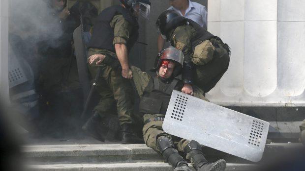 Ukrajinští policisté odnášejí kolegu zraněného při výbuchu granátu před ukrajinským parlamentem