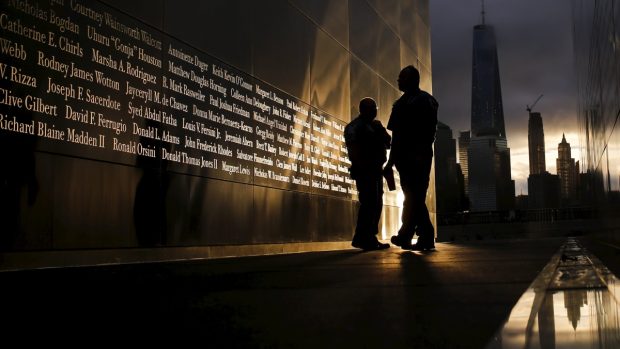 Lidé si u památníku na dolním Manhattanu čtou jména obětí teroristického útoku na WTC