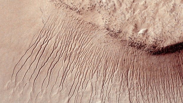Vědci objevili na Marsu tekoucí vodu. Slaná voda při teplejším období pravděpodobně vytéká zpod povrchu a vytváří stopy v krajině, takzvané černé pruhy (ilustrační foto)