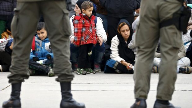 Členové rakouské armády střeží skupinu migrantů čekající na hranicích ve Spielfeldu