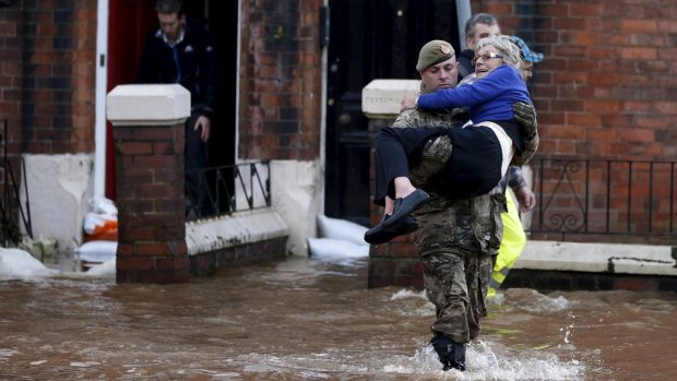 Voják pomáhá obyvatelce zaplaveného domu v Carlisle