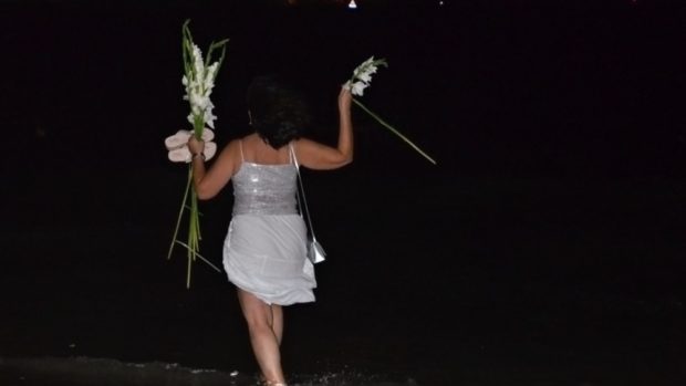 Silvestr 2014. Žena v bílém oblečení hází bílé květy do moře
