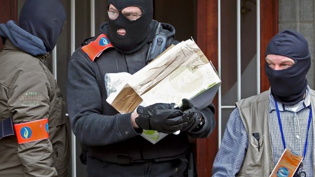 Maskovaní belgičtí policisté odnášejí balíček z budovy v bruselské čtvrti Anderlecht