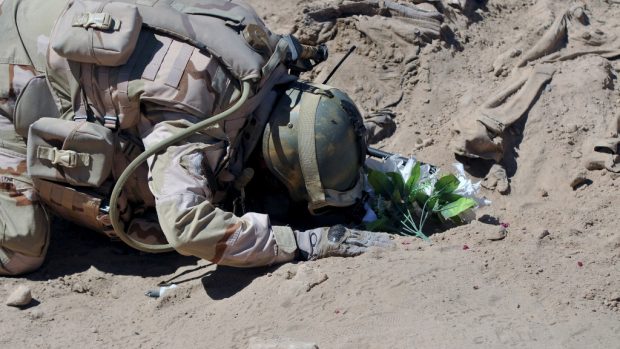 Irácký voják se modlí u masového hrobu u šíitských vojáků ze základny Speicher