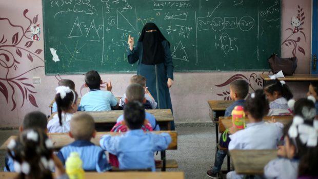 Palestinská učitelka se zahaleným obličejem vyučuje žáky ve škole v Pásmu Gazy (snímek z prvního školního dne, který tu měli už 28. srpna)