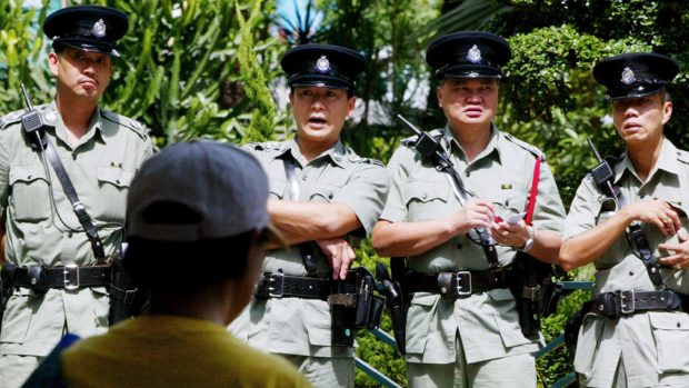 Policisté v Hongkongu dohlížejí na meditaci příznivců hnutí Fa-lun Kong, která proběhla během protestní hladovky v srpnu 2002. Hnutí je v Číně pronásledované.