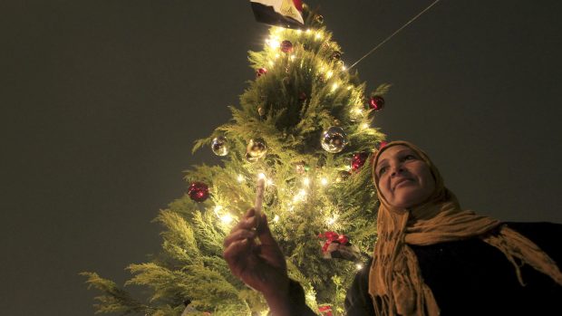 Muslimská žena zapaluje svíčku u vánočního stromu v Káhiře (archivní foto)