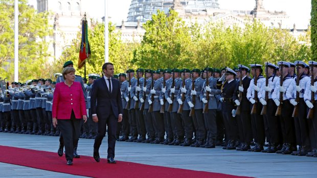 Nový francouzský prezident Emmanuel Macron si společně s německou kancléřskou Angelou Merkelovou prohlíží nastoupené jednotky při návštěvě v Berlíně.