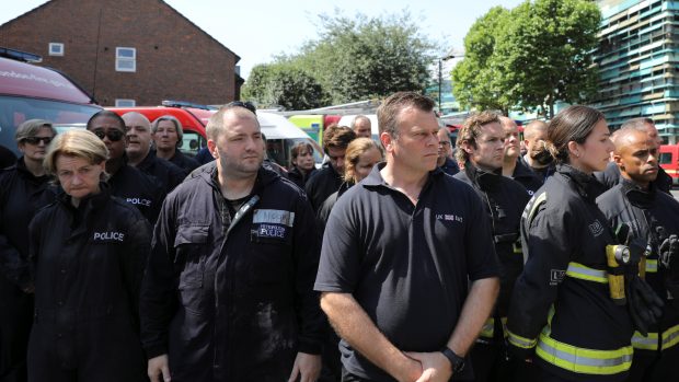 Zdravotníci a policisté během minuty ticha za oběti požáru v Grenfell Tower.