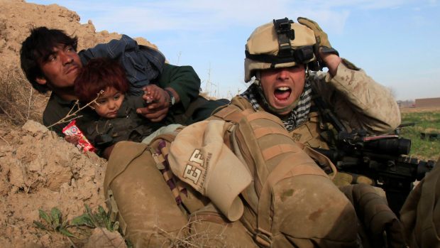 Křičící americký voják se snaží bránit Afghánce a jeho dítě před palbou ozbrojenců Tálibánu během bitvy o město Mardžah (archivní snímek ze 13. února 2010).