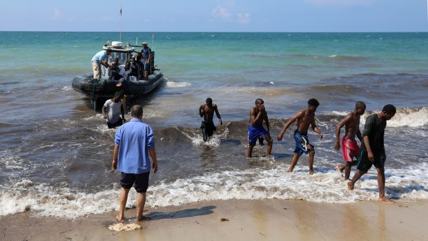 Migranti opouští záchranářskou loď na pobřeží u Tripolisu (19.6.2018)