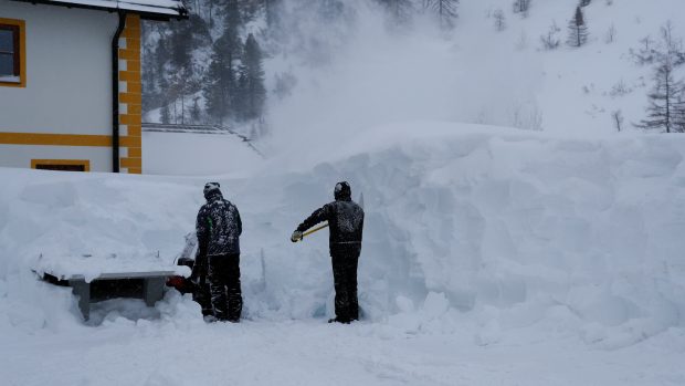 Dva muži odklízejí sníh po sněhové vánici v rakouském lyžařském centru Obertauern