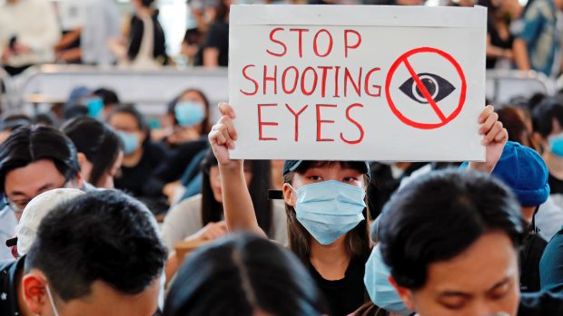 Někteří demonstranti na letišti mají pásky přes pravé oko, na transparentech se objevují nápisy „Nestřílejte do očí“ nebo „Zastavte ten masakr“.