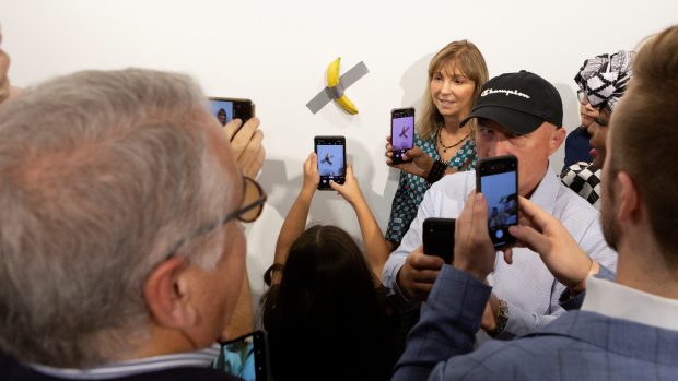 Návštěvníci galerie v Miami se fotí u banánu přelepeného lepicí páskou, který se prodal za 120 tisíc dolarů.