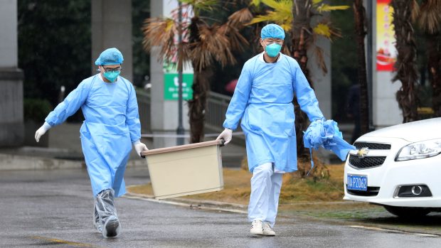 Dvojice zdravotníků odnáší kontaminovaný materiál z nemocnice ve Wu-chanu, kde jsou hospitalizováni pacienti s novým koronavirem