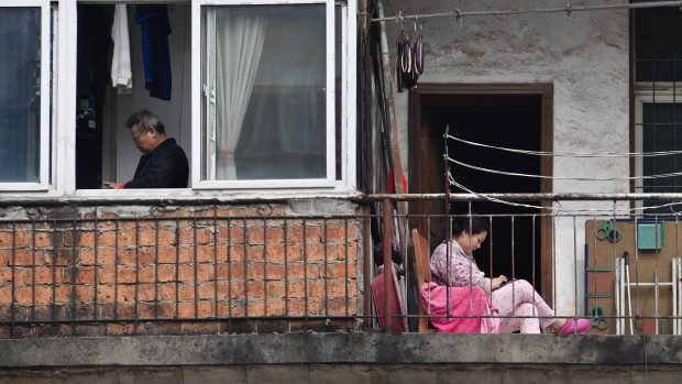 Žena a muž sledují své mobilní telefony zatímco kvůli šíření nového koronaviru tráví uzavírku města Wu-chan ve svém domově (foto z března 2020)