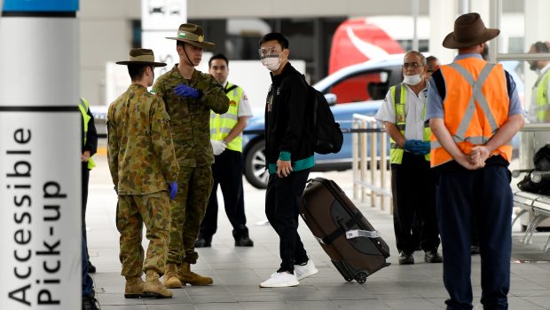 Australští vojáci kontrolují cestující, kteří přiletěli na letiště v Sydney.