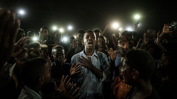 Vítězný snímek World Press Photo. Japonský fotograf Yasujoši Čiba snímek nazval Straight Voice (Jasný hlas). Uprostřed je mladý muž v Súdánu, jenž loni v červenci mezi demonstranty a v záři světel z mobilních telefonů recitoval básně.