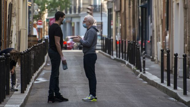 Dvojice mužů v rouškách na pařížské ulici.