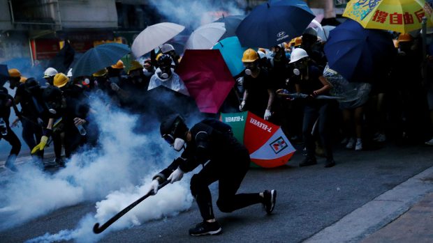Demonstrant se snaží odpálit zpět  kapsli se slzným plynem, který policie v Hongkongu použila k rozehnání  demonstrace proti zákonu o národní bezpečnosti navrhovanému Pekingem.